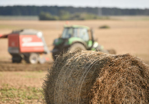 Tractor cleans the field with flax and makes bales